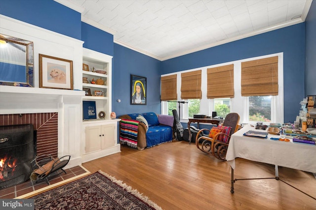 bedroom with a brick fireplace, multiple windows, crown molding, and wood finished floors