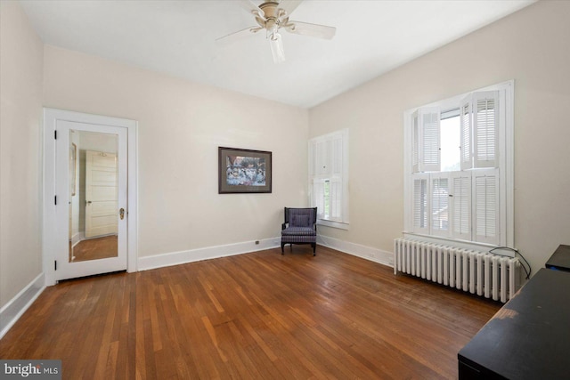 unfurnished room with dark wood-style floors, ceiling fan, radiator heating unit, and baseboards