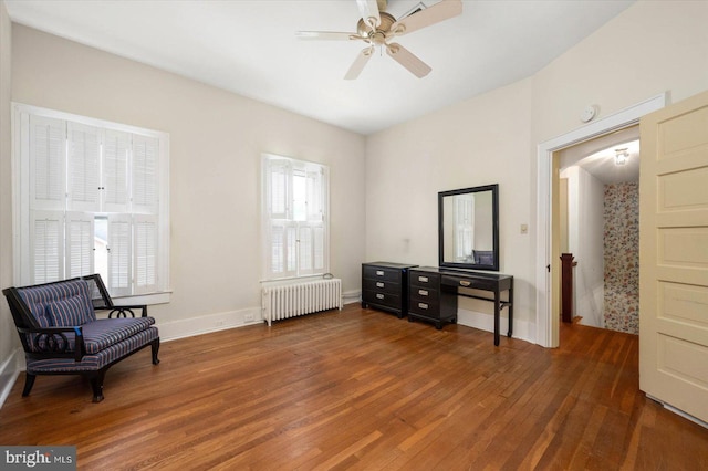 sitting room with baseboards, radiator heating unit, a ceiling fan, and dark wood-style flooring