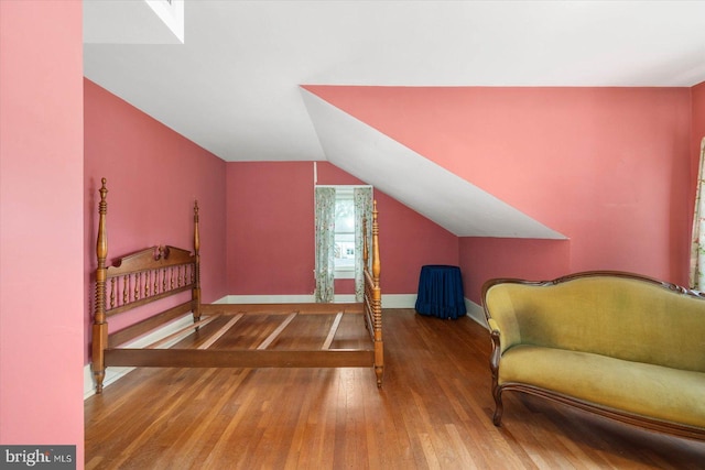 bedroom featuring lofted ceiling, wood finished floors, and baseboards