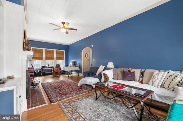 living room with ceiling fan, crown molding, arched walkways, and wood finished floors