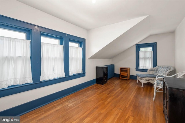 living area with baseboards, vaulted ceiling, and wood finished floors