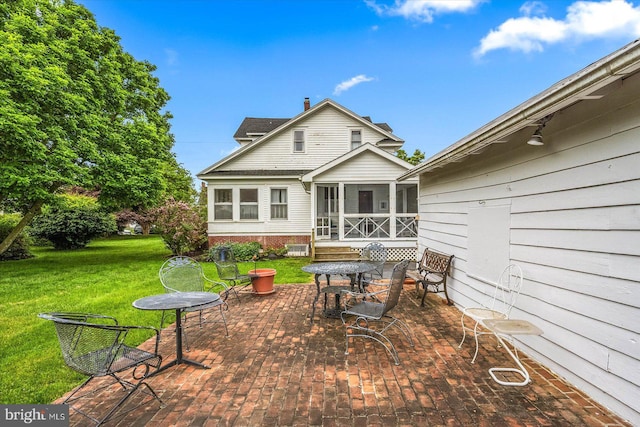 back of house with a yard, a sunroom, a patio, and outdoor dining area