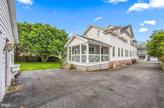 view of side of home with a sunroom, fence, and a yard