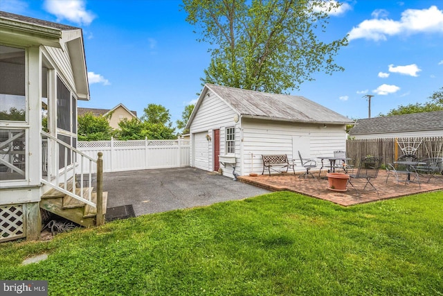 view of yard with a detached garage, a patio, fence, an outdoor structure, and a fire pit