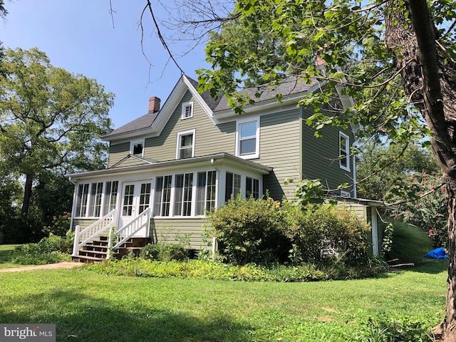 view of front facade featuring a front lawn and a sunroom