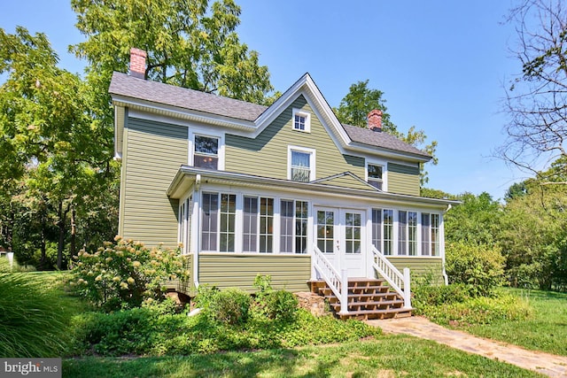 view of front facade with a sunroom and a chimney