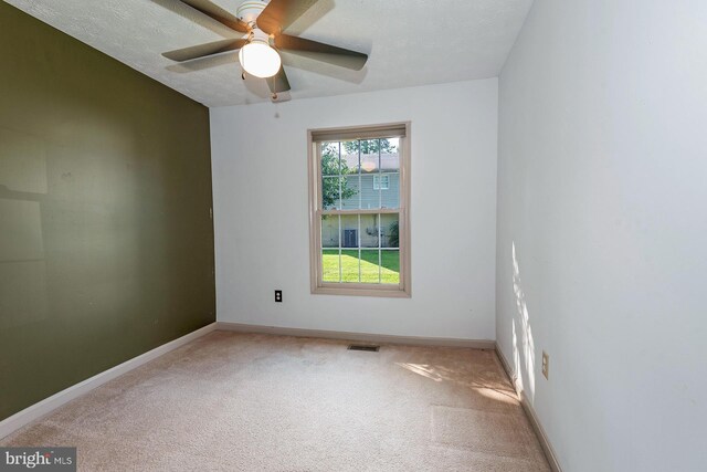 empty room with ceiling fan, a textured ceiling, light carpet, and a healthy amount of sunlight