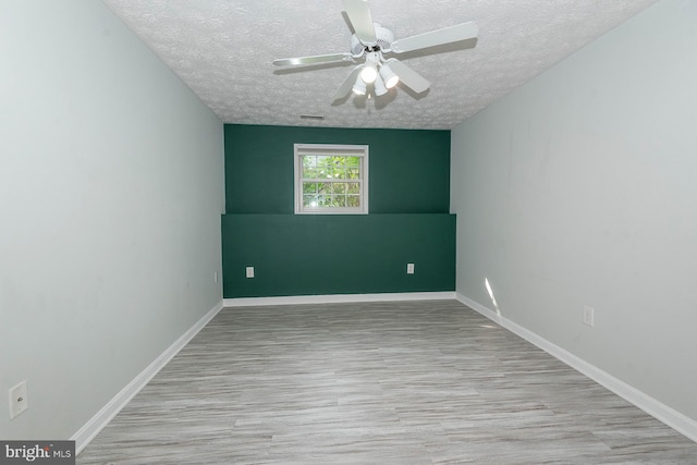 spare room featuring ceiling fan, light hardwood / wood-style flooring, and a textured ceiling