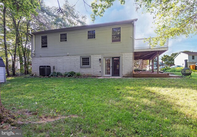 rear view of house featuring a deck, a lawn, and cooling unit