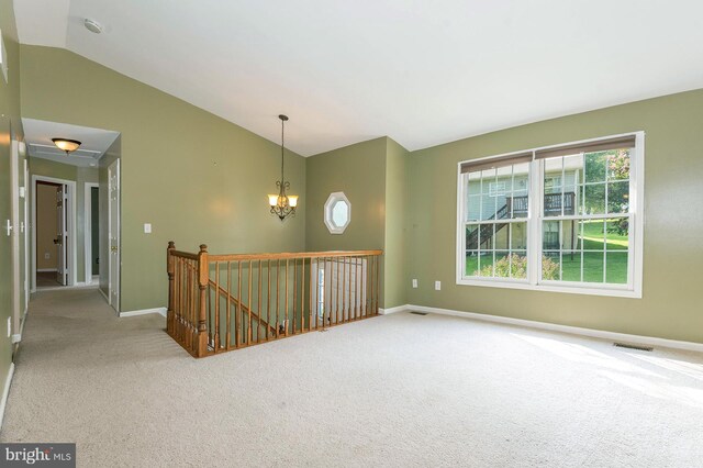 unfurnished room featuring plenty of natural light, vaulted ceiling, an inviting chandelier, and carpet