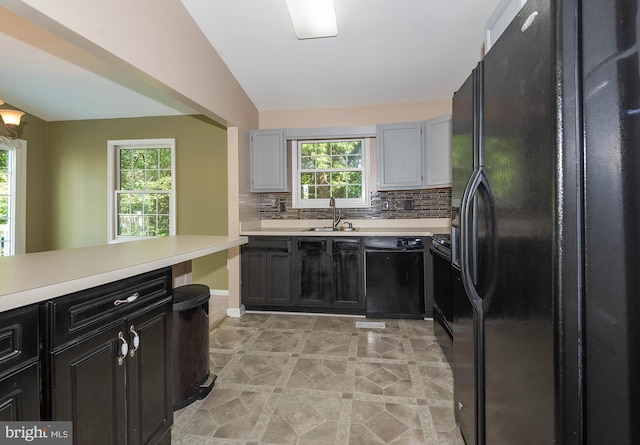 kitchen featuring sink, vaulted ceiling, tasteful backsplash, light tile patterned floors, and black appliances