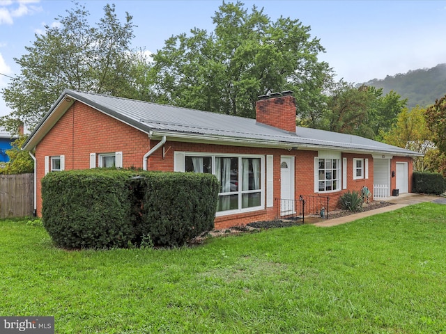 view of front of home with brick siding, a chimney, metal roof, a garage, and a front lawn