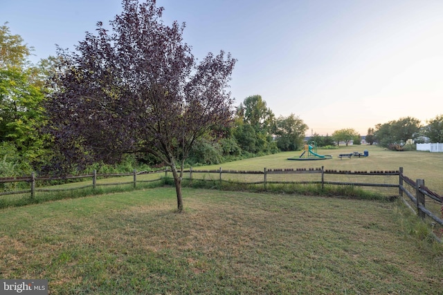 yard at dusk featuring a playground