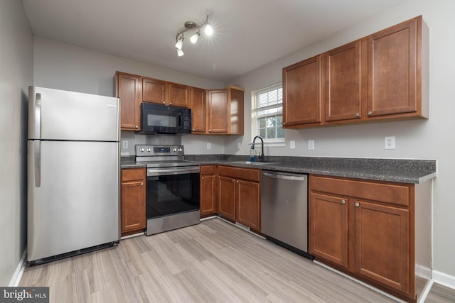 kitchen with light wood-type flooring, appliances with stainless steel finishes, and sink