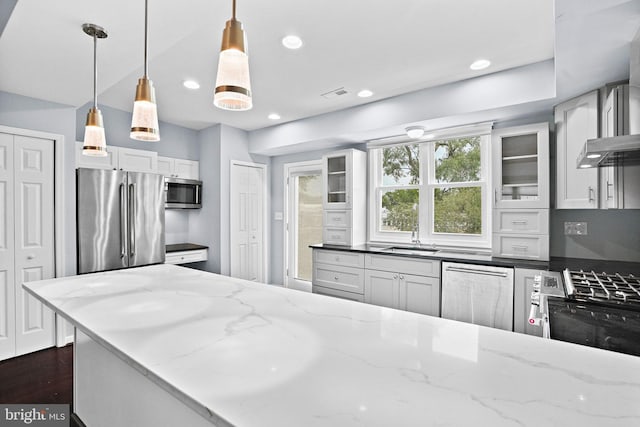 kitchen with appliances with stainless steel finishes, light stone countertops, white cabinetry, and hanging light fixtures