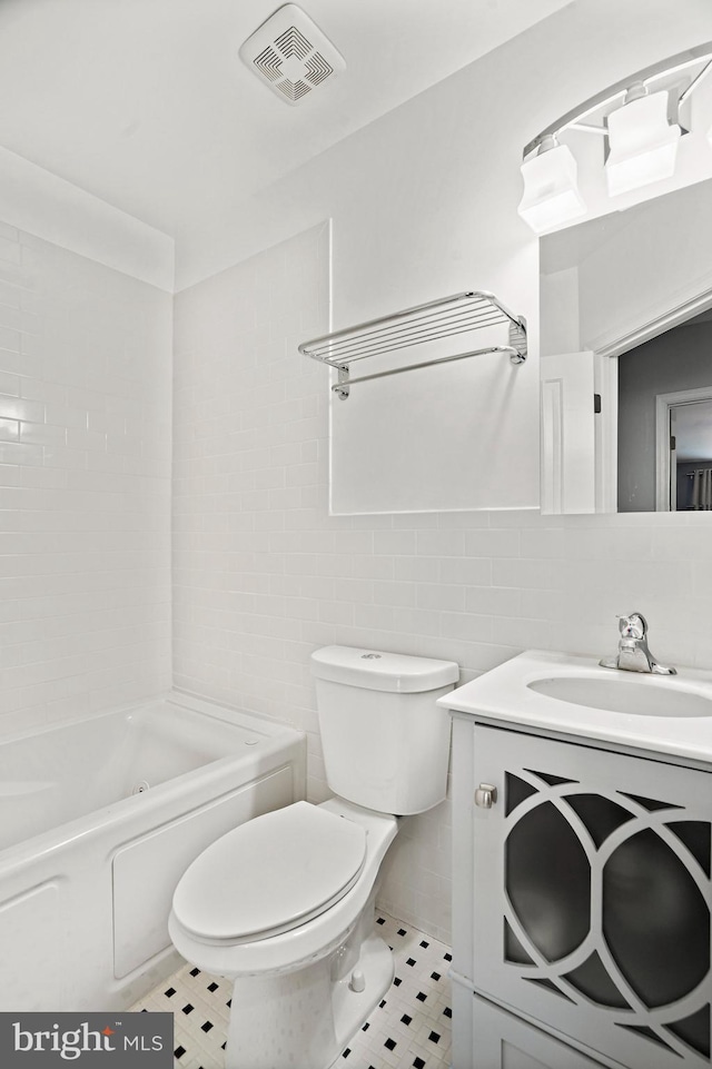 full bathroom with vanity, tile walls, toilet, tile patterned floors, and tiled shower / bath combo