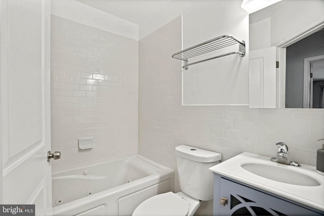 full bathroom featuring tile walls, tiled shower / bath, toilet, and vanity