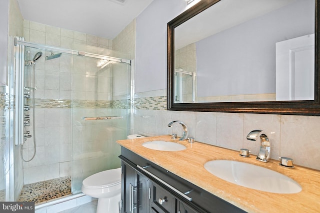 bathroom with toilet, a shower with door, vanity, tasteful backsplash, and tile walls