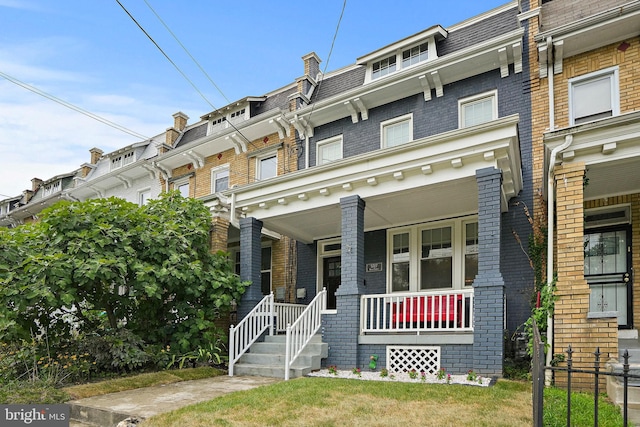 townhome / multi-family property featuring a porch and a front lawn