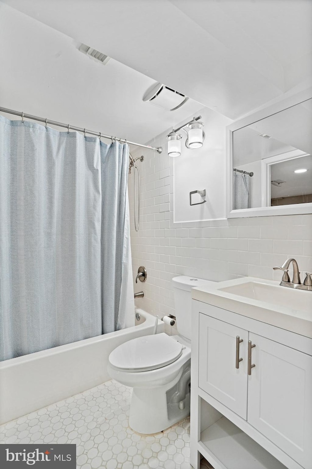 full bathroom featuring toilet, tile patterned floors, vanity, shower / bathtub combination with curtain, and tile walls