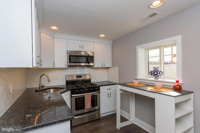 kitchen with appliances with stainless steel finishes, sink, white cabinets, dark hardwood / wood-style flooring, and dark stone countertops