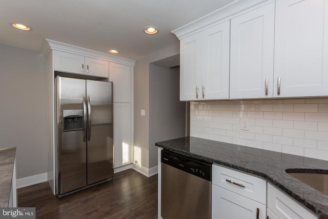 kitchen with stainless steel appliances, dark wood-style floors, white cabinetry, backsplash, and dark stone counters