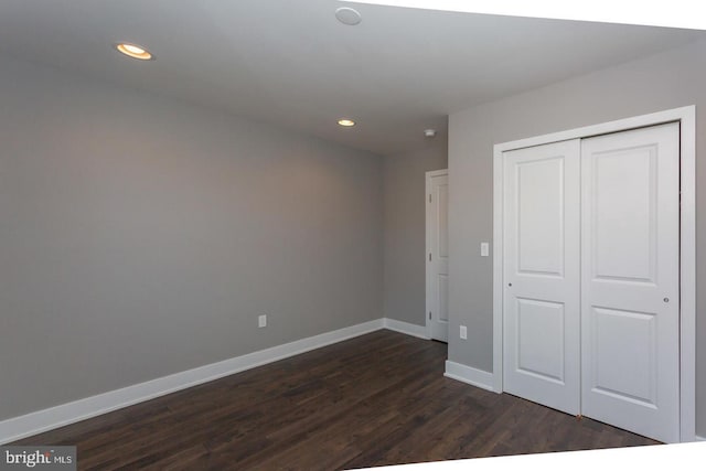 unfurnished bedroom featuring dark wood-type flooring, recessed lighting, a closet, and baseboards