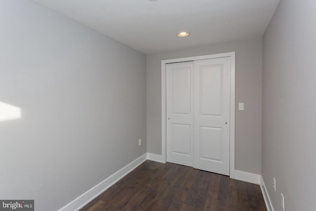 unfurnished bedroom featuring dark wood-type flooring, recessed lighting, a closet, and baseboards