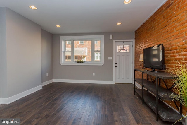 foyer with dark hardwood / wood-style flooring and brick wall