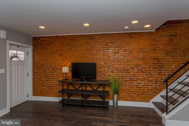 living area with dark wood-type flooring, recessed lighting, stairway, and brick wall