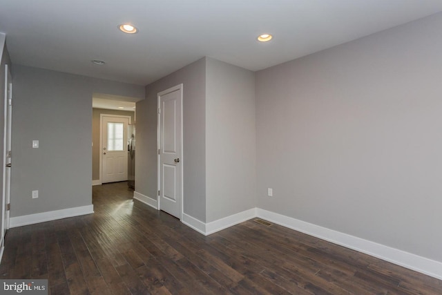 spare room with dark wood-type flooring, recessed lighting, and baseboards