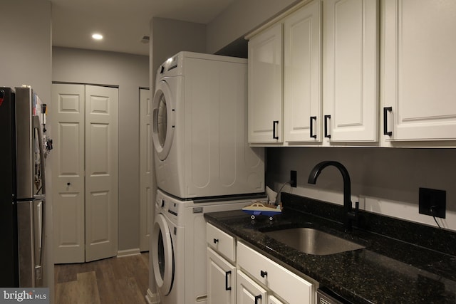 clothes washing area with dark hardwood / wood-style floors, sink, and stacked washer / dryer