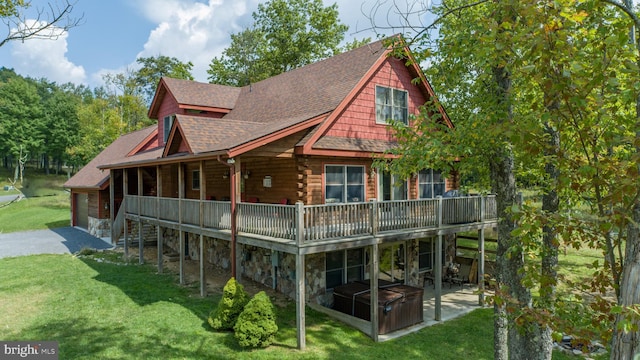 rear view of house featuring a jacuzzi, a lawn, and a patio area