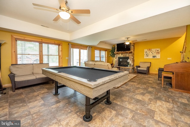 recreation room with a stone fireplace, billiards, a ceiling fan, and baseboards