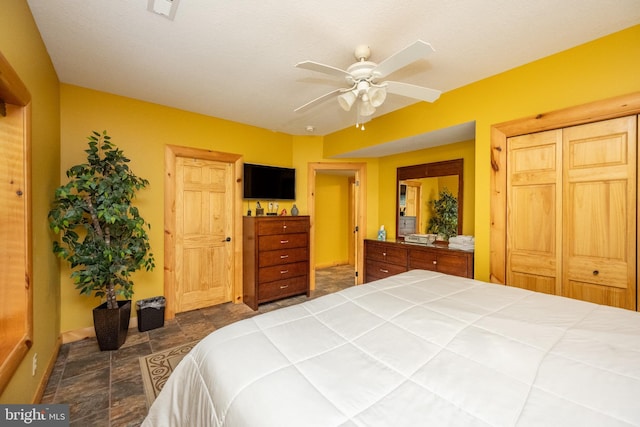 bedroom with stone finish flooring, baseboards, and a ceiling fan