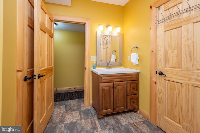 bathroom featuring stone finish floor, baseboards, and vanity