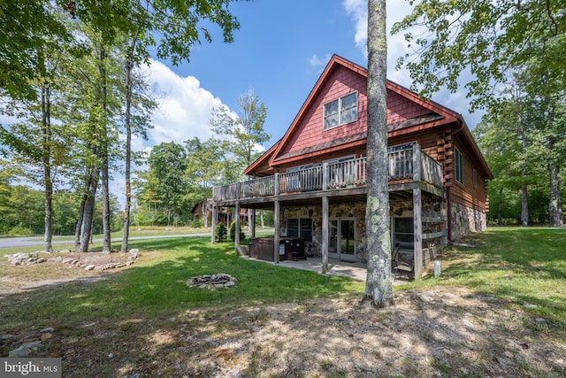 rear view of house with log exterior, a lawn, a patio, stone siding, and a deck