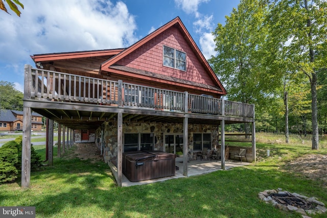 rear view of house with a hot tub, a lawn, a patio, stone siding, and a wooden deck