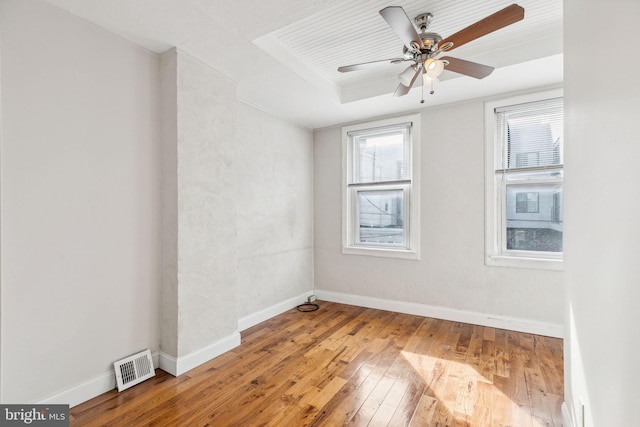 spare room featuring ceiling fan, hardwood / wood-style flooring, and a tray ceiling