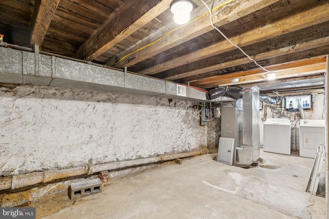 basement featuring heating unit, electric panel, and washing machine and clothes dryer