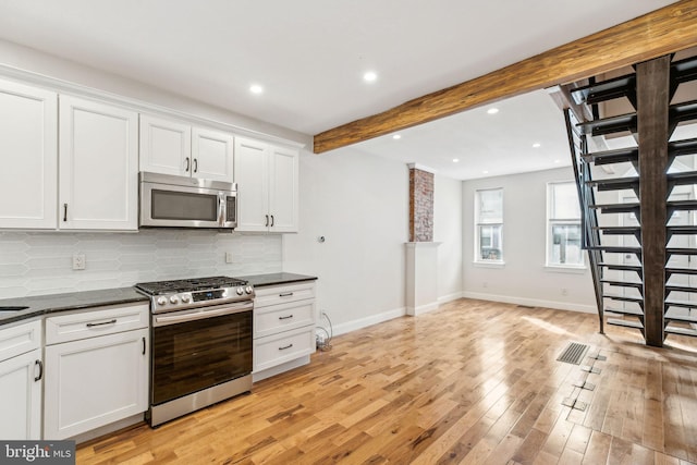 kitchen featuring light wood-type flooring, beamed ceiling, tasteful backsplash, white cabinetry, and stainless steel appliances