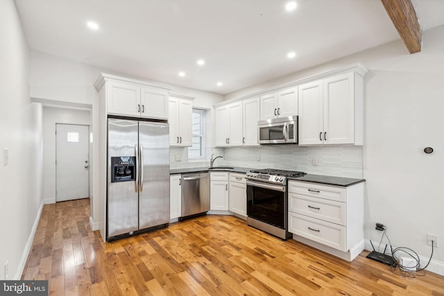 kitchen featuring beamed ceiling, sink, white cabinetry, light hardwood / wood-style flooring, and stainless steel appliances