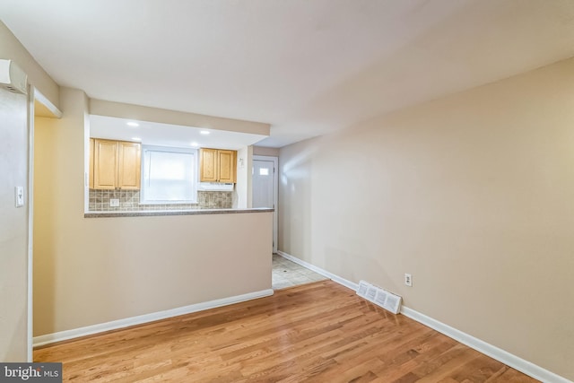 unfurnished living room with light wood-style flooring, visible vents, and baseboards