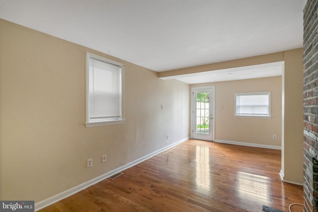 spare room featuring light wood-style flooring, a fireplace, visible vents, and baseboards