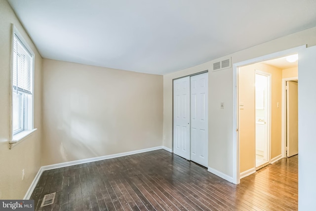 unfurnished bedroom with visible vents, dark wood finished floors, and baseboards