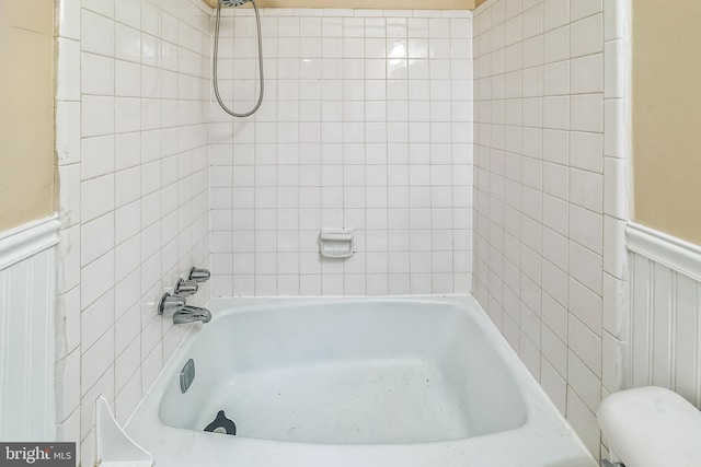 bathroom with toilet, bathing tub / shower combination, and wainscoting