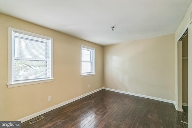 unfurnished bedroom with dark wood-style floors, baseboards, visible vents, and a closet