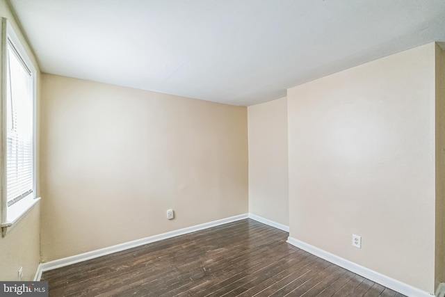 unfurnished room with baseboards and dark wood-style flooring