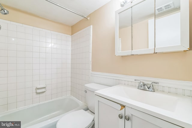 bathroom with visible vents, toilet, washtub / shower combination, wainscoting, and vanity